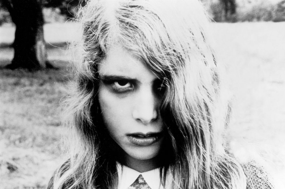 A young, undead woman, with dark circles around her eyes, her hair nearly covering one eye, staring blankly at the camera.
